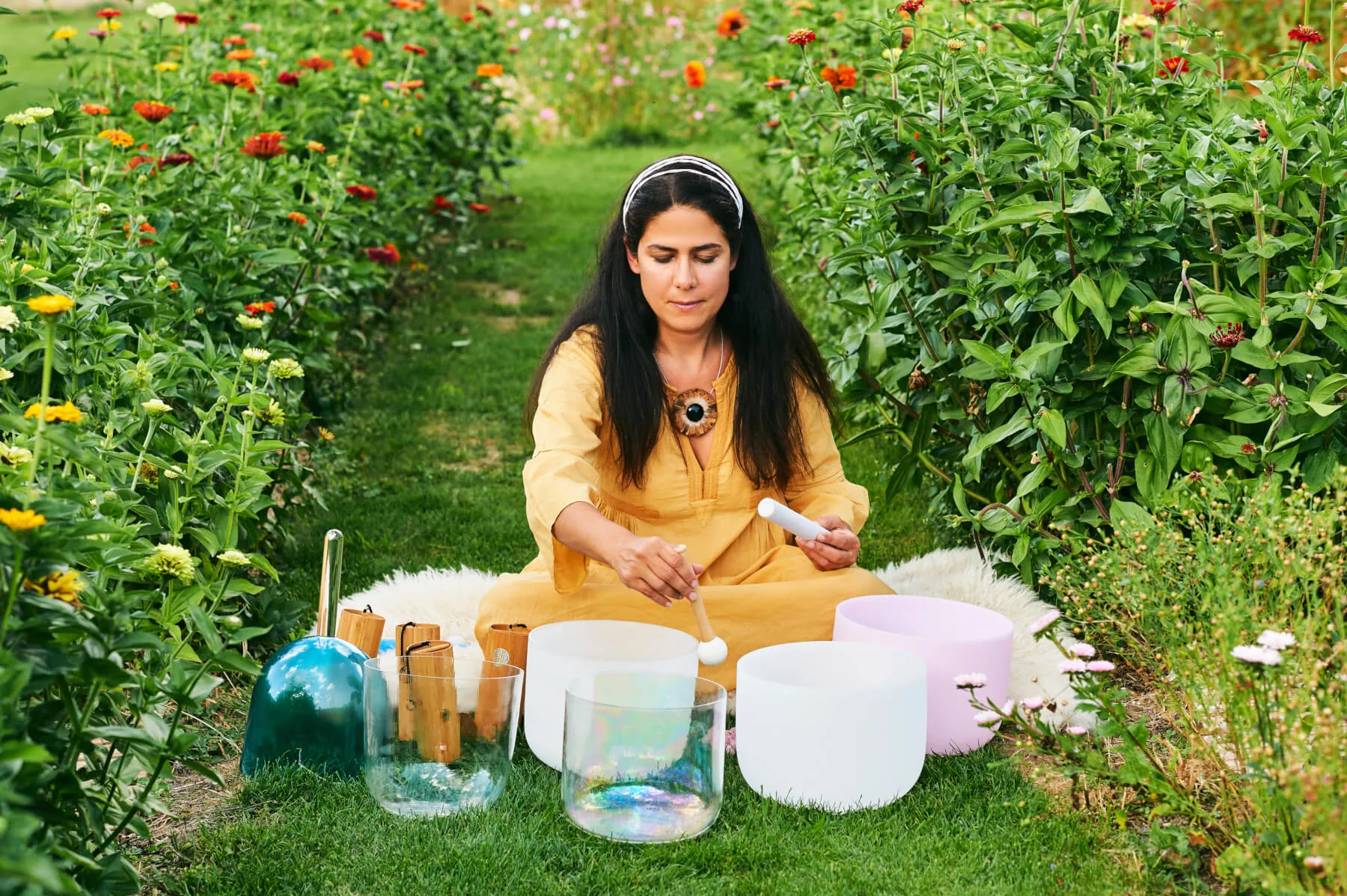 Kristallklangschalen werden von einer Frau im Garten gespielt