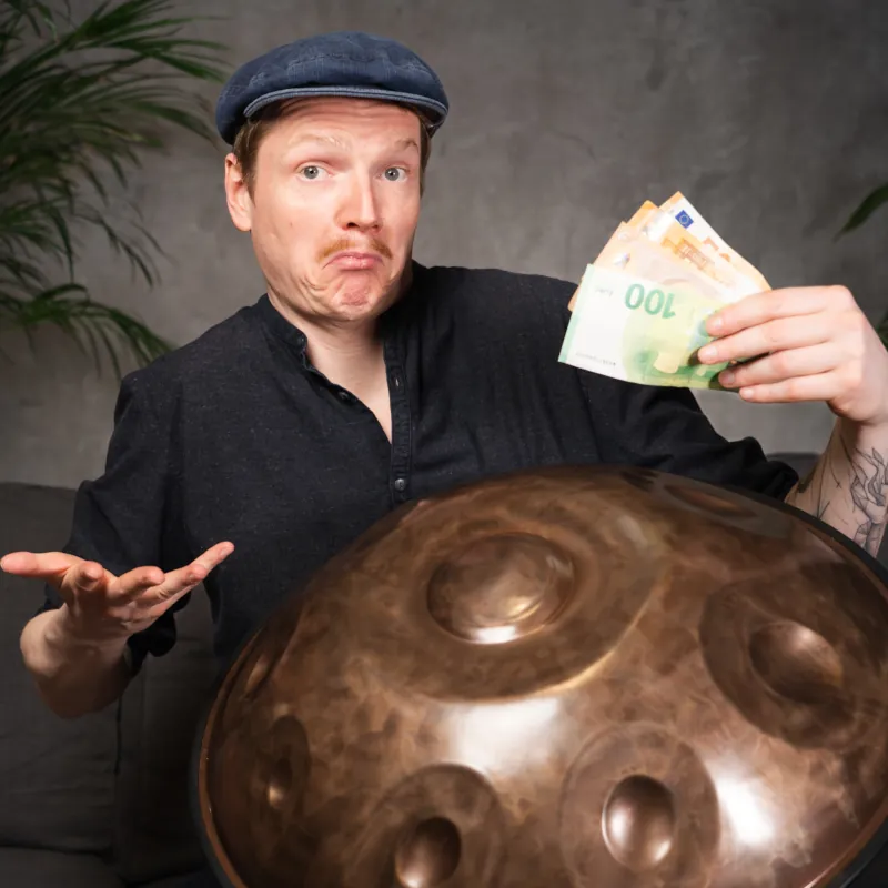 Handpan Preis – Mann mit Handpan im Schoß und Geld in der Hand