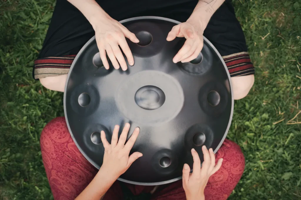 Zwei Personen spielen Handpan bei einem Handpan-Kurs im Garten