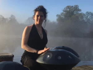 petra kleinecke spielt handpans, tongue drum und trommel auf einem steg am see